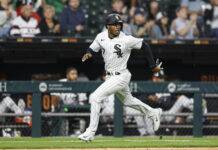 Two-time All-Star and Batting Champion Announces Retirement Baseball player in a white pinstripe White Sox uniform running on the field with a ballpark crowd in the background, mid-stride in a game.