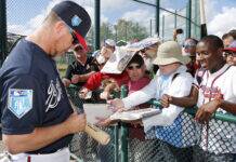 Braves Icon Chipper Jones Announces Heartfelt Personal News Baseball players sign autographs for fans pressed against a chain-link fence, pens and papers in hand.