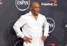 Mike Tyson Has MLB Fans Stunned After Awkward Hot Mic Moment Man in a white button-down shirt posing with hands on hips at the ESPYS backdrop.