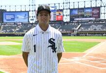 MLB No. 1 Draft Pick Bursts Into Tears As He Is Selected Baseball player in White Sox pinstriped jersey with number 1, standing on the infield with empty stands behind him.