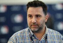 Braves Among Contenders to Push for Reigning Cy Young Winner Close-up portrait of a man with dark hair and a gray beard, wearing a blue-checkered shirt and a lanyard, with a blurred background