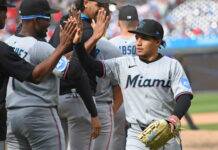 Marlins Rout Braves 12-0, What Went Wrong? Baseball players from Miami team high-fiving during a game, wearing gray uniforms and black caps.
