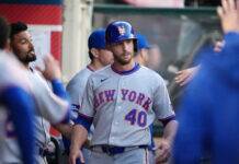 New York Mets Ditch ex-Yankees Flop After Just a Month Baseball player in a gray New York Mets uniform wearing a blue helmet with an orange NY logo, standing in the dugout with teammates nearby.